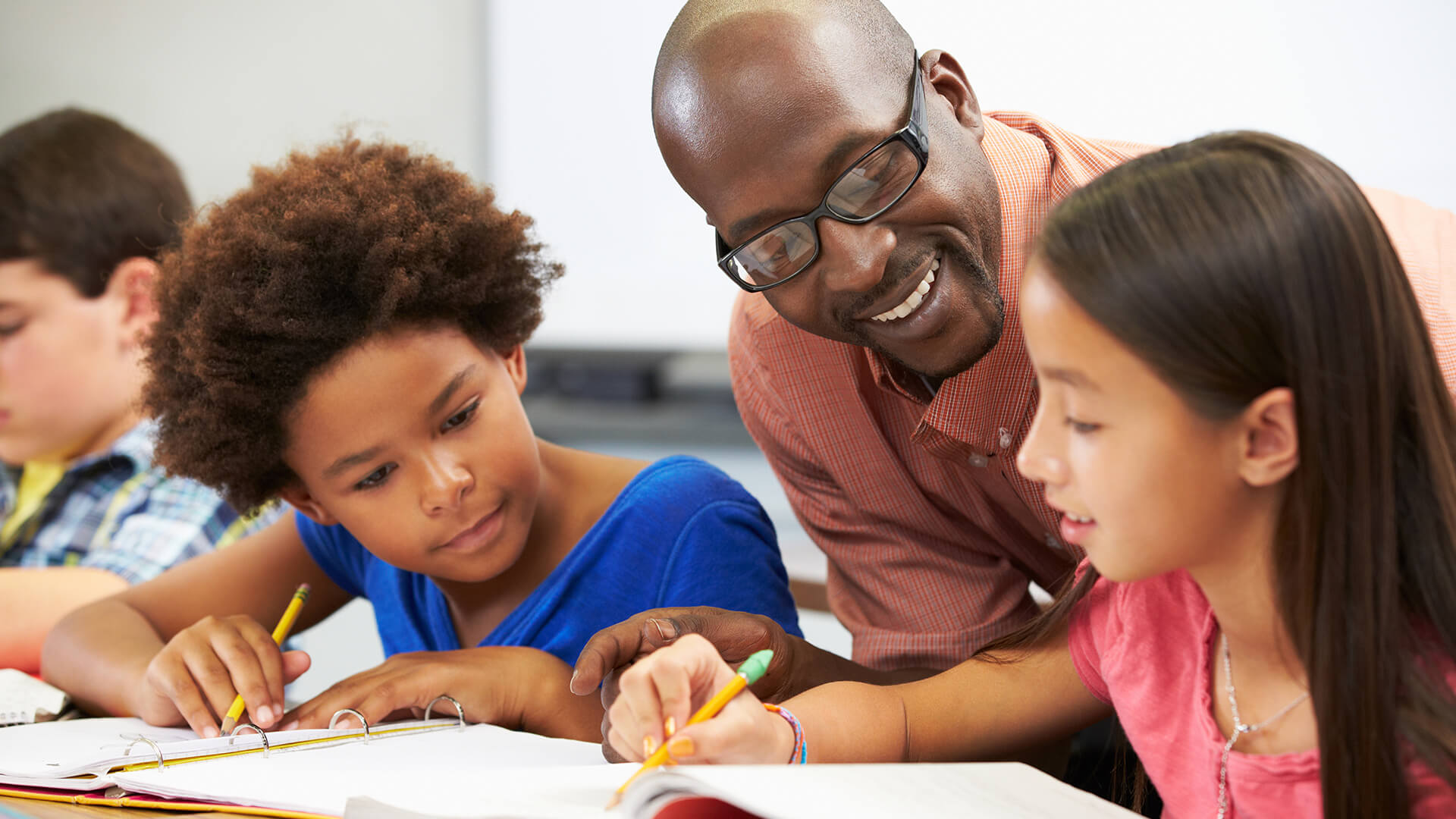 Teacher helping two students at their desk