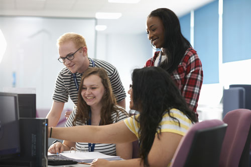 Les élèves et leur enseignante travaillent ensemble sur un ordinateur